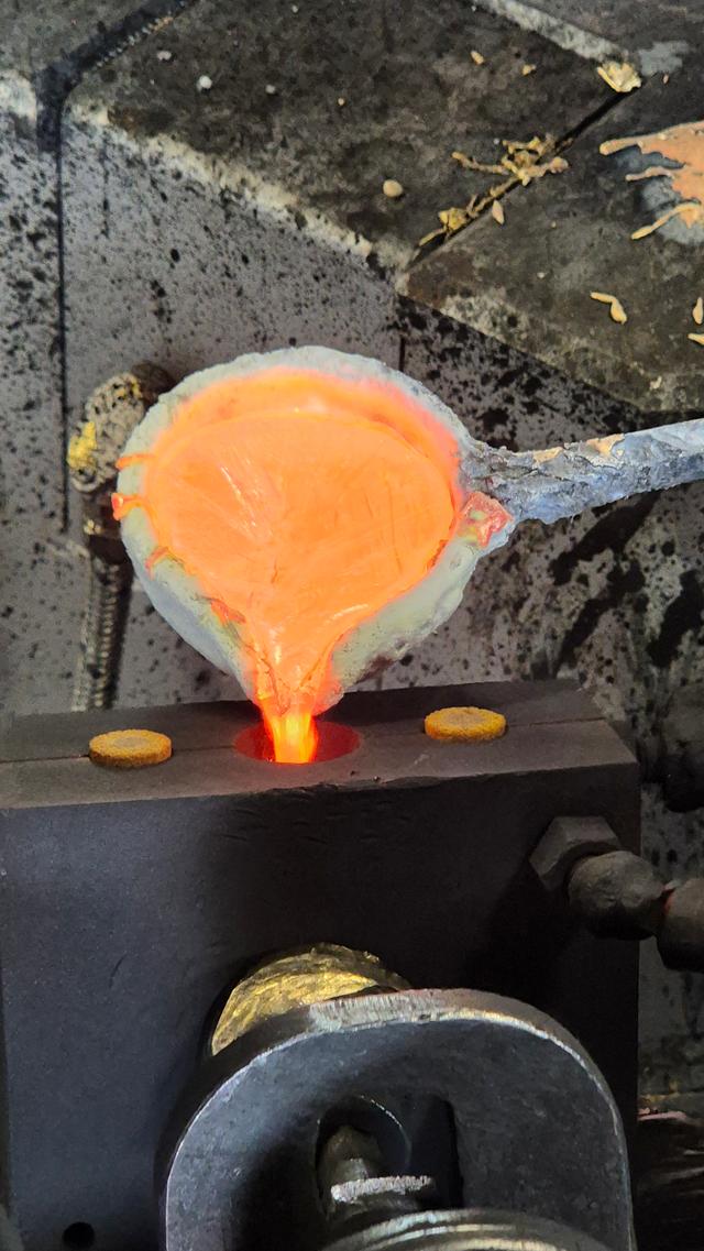 Molten brass being poured into a mold during casting