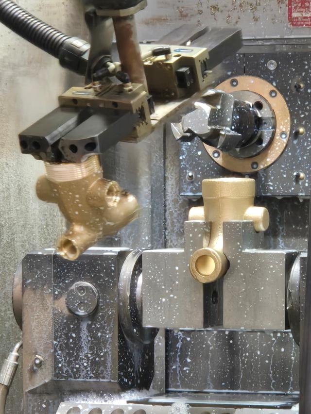 A brass part being machined on a lathe with coolant