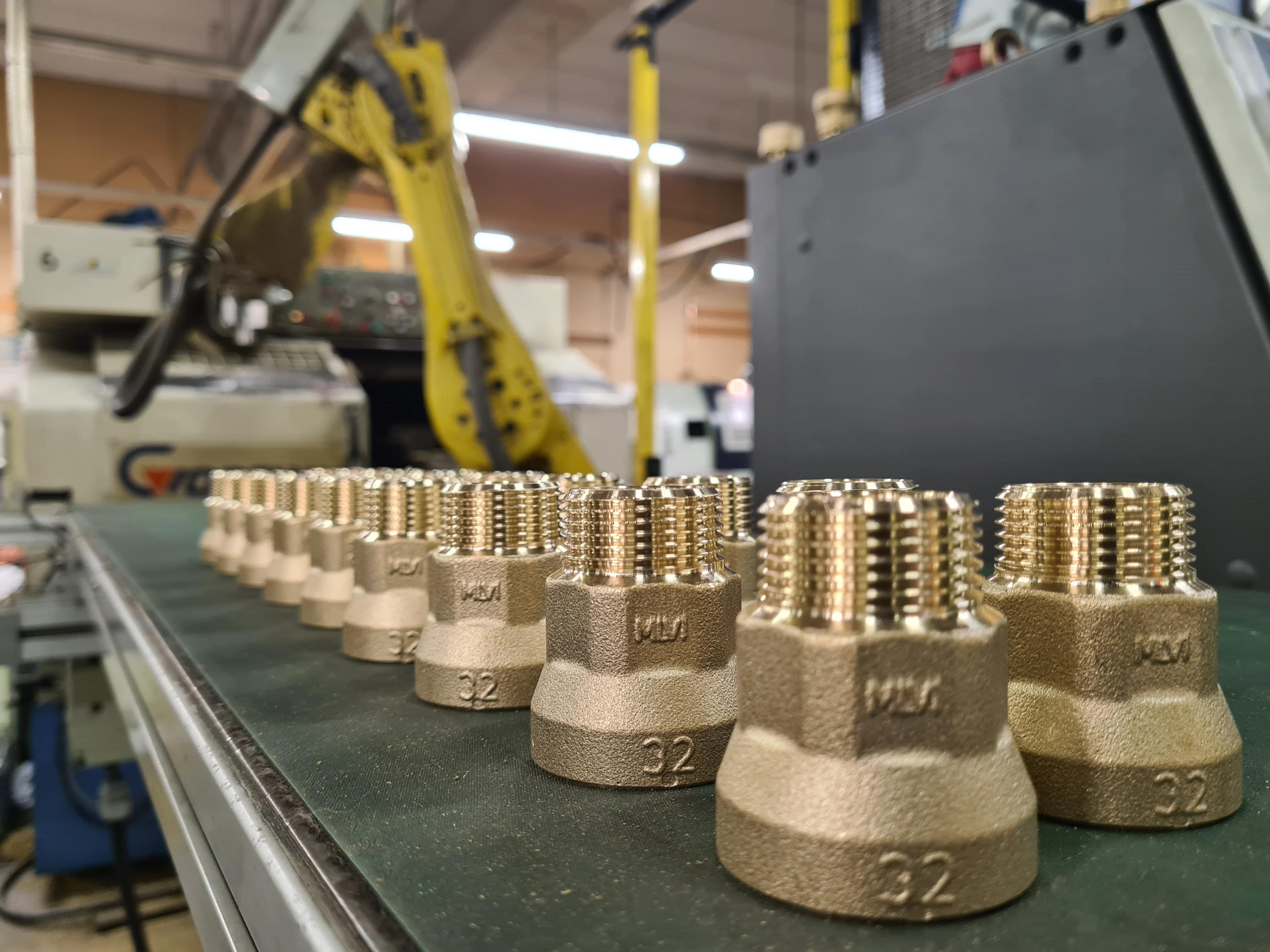 Rivi messinkisiä kierreosia tuotantolinjalla